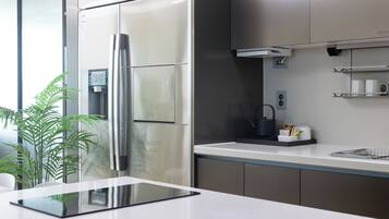 Een moderne keuken met roestvrijstalen apparatuur, een wit aanrecht en een kleine plant.
