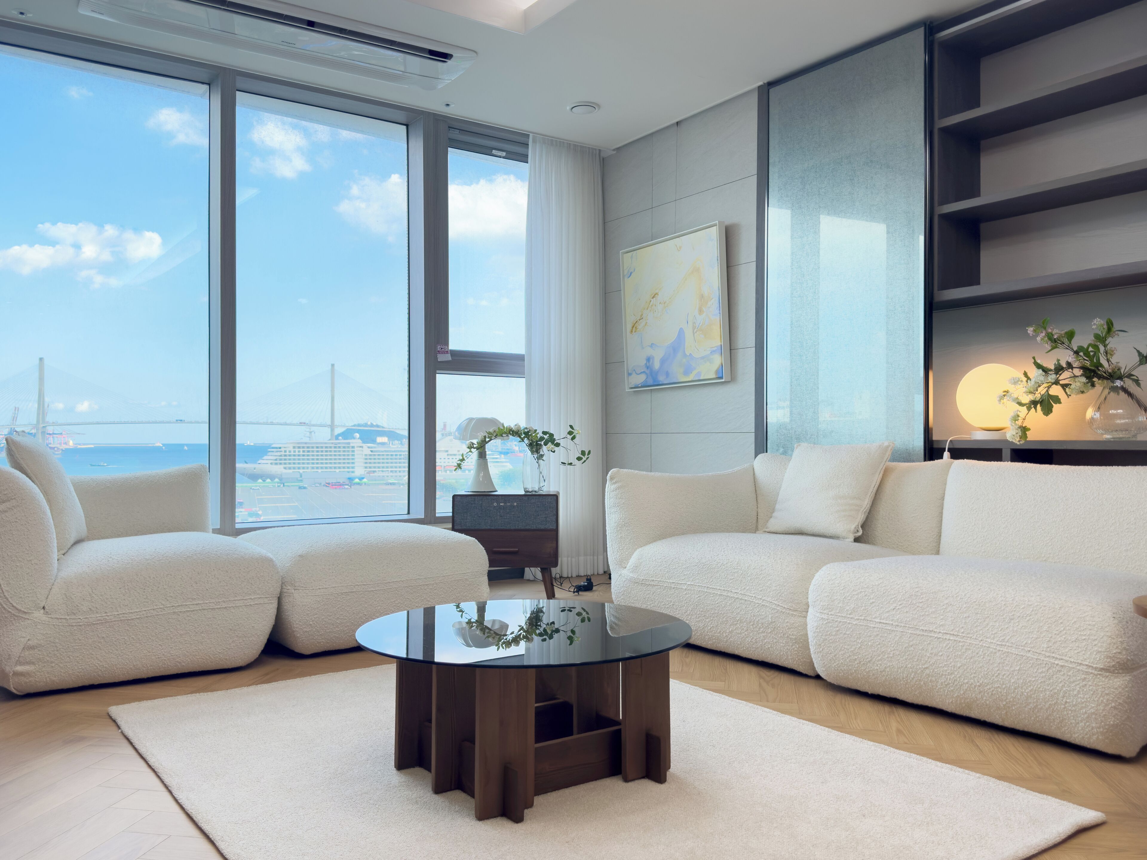 A modern living room with a large window, two sofas, a coffee table, and a decorative vase.