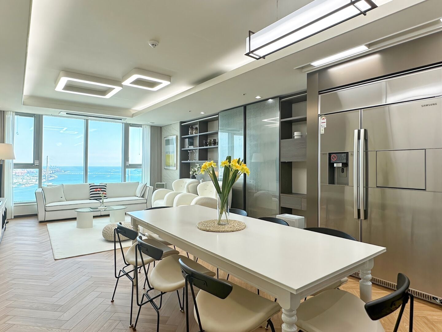 A modern kitchen with a white table, chairs, and a refrigerator.
