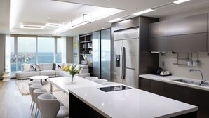 Une cuisine moderne dotée d’un grand îlot central, d’appareils électroménagers en acier inoxydable et offrant une vue sur la ville.