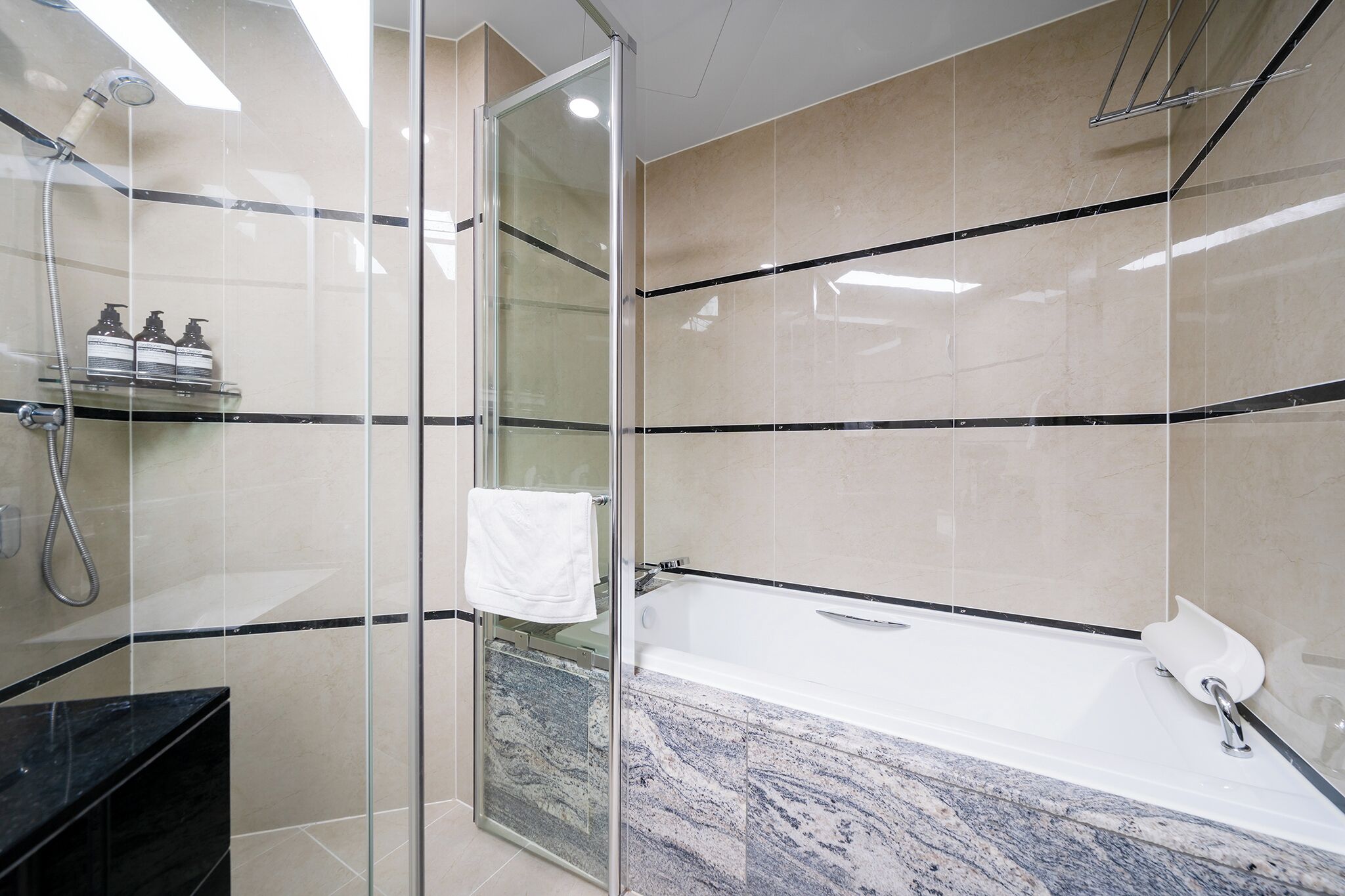 A modern bathroom with a glass-enclosed shower, a marble sink, and a bathtub.