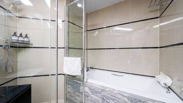 A modern bathroom with a glass-enclosed shower, a marble sink, and a bathtub.