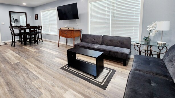 A modern living room with a grey sofa, a black coffee table, and a wooden dining table with chairs. - Studio "Grande" (Lakeland)