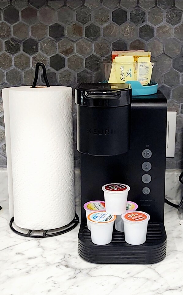 Una cafetera amb un dispensador de paper de cuina, un rebedor de rajoles hexagonals i quatre tasses de iogurt.