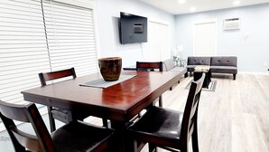 A dining area with a wooden table and chairs, a large vase, and a flat-screen TV mounted on the wall. - Studio "Grande" (Lakeland)