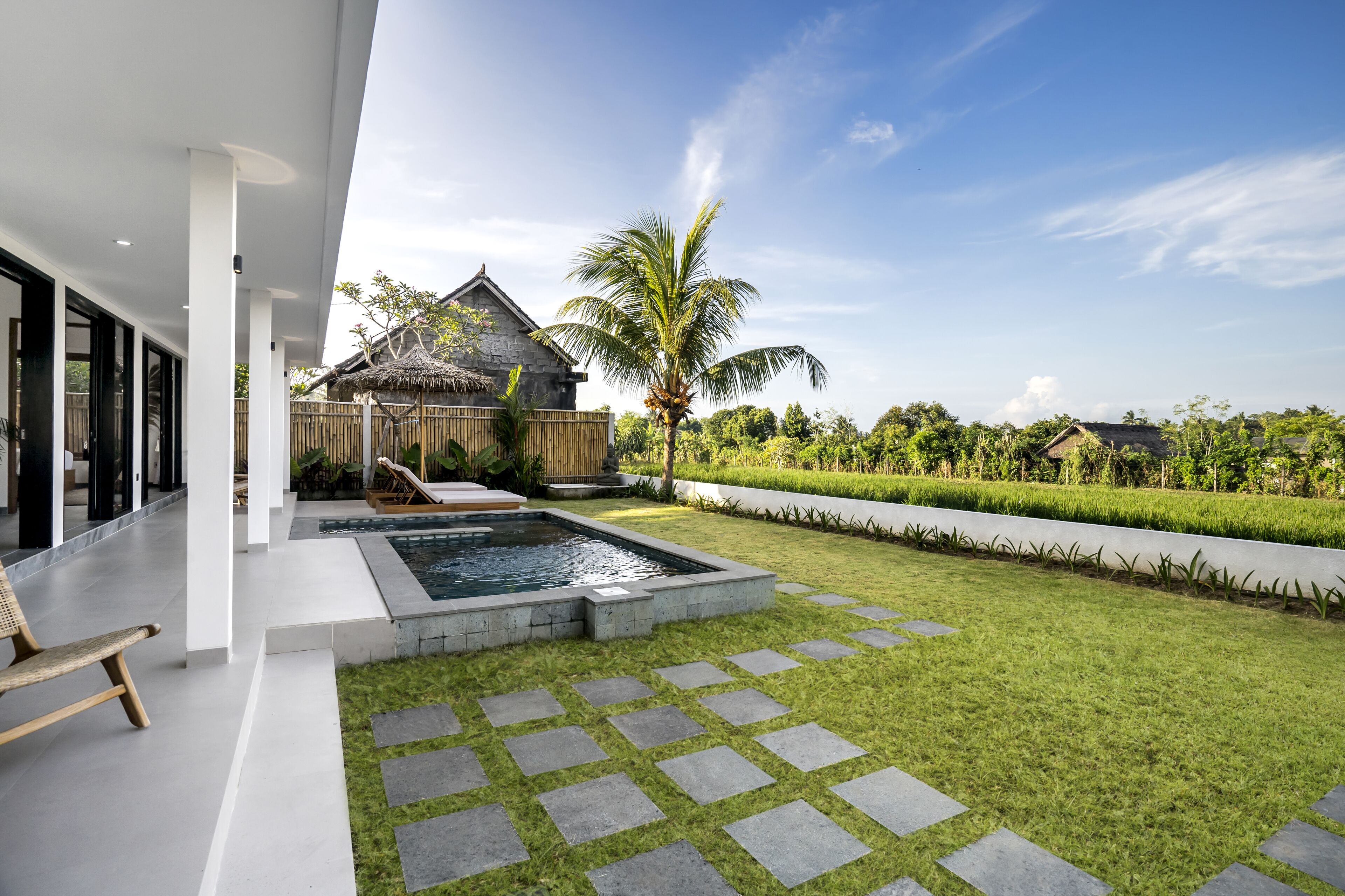 A modern outdoor area with a swimming pool, stone pathway, and a wooden deck with lounge chairs.