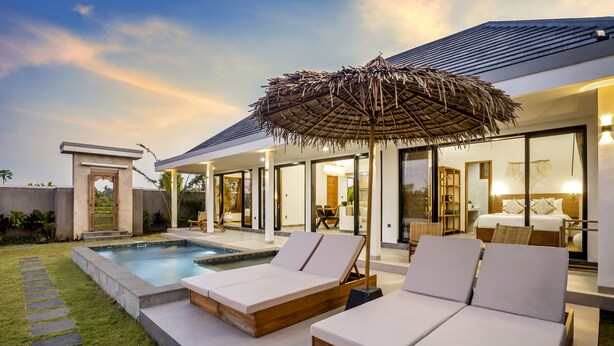 A modern house with a swimming pool, lounge chairs, and a large umbrella. - Villa Grateful by Alfred in Bali (Sukawati)