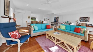 Amplia sala de estar con un sofá azul, una mesa de centro de madera y un sillón de mimbre.