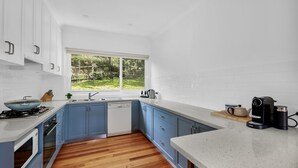 Una cocina moderna con armarios azules, suelo de madera y ventana con vistas a un jardín.
