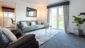 A modern living room with a grey sofa, a leather armchair, and a glass coffee table. - Manchester - House - (Manchester)