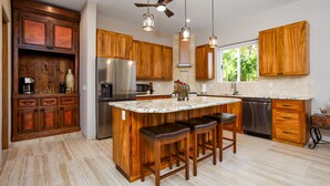 Una cocina con armarios de madera, un refrigerador de acero inoxidable, un lavavajillas y una isla grande con taburetes de bar.