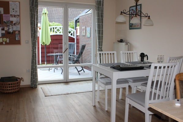 A dining area with a table, chairs, and a view through a glass door to an outdoor patio.