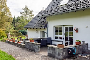 Ein Haus mit Terrasse, Sitzgelegenheiten im Freien und Blumentöpfen.