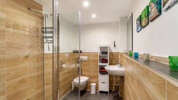 A modern bathroom with a glass shower enclosure, a white sink, and a wooden vanity.