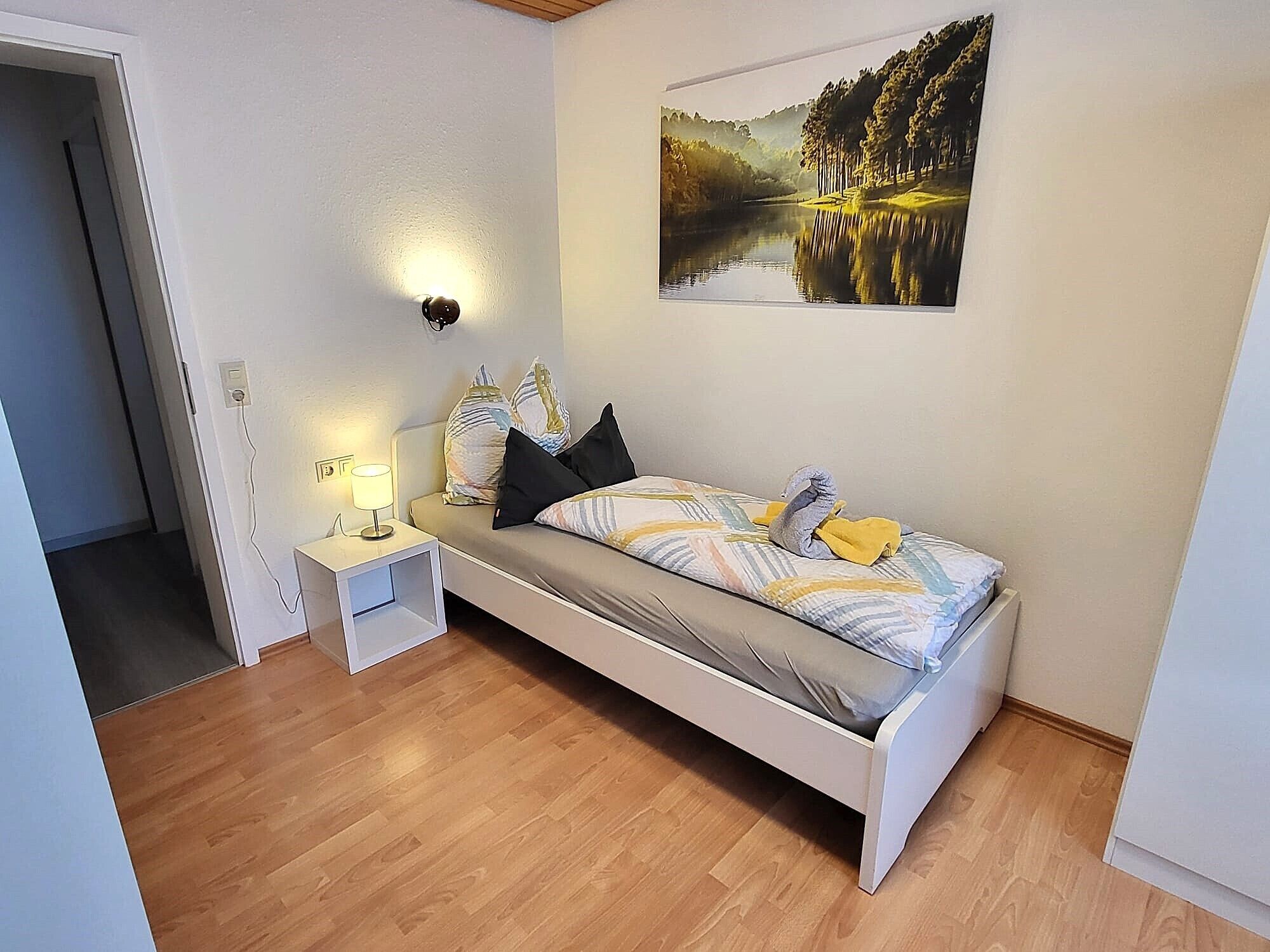 Une chambre à coucher avec un lit, une table de chevet, une lampe et un tableau accroché au mur.