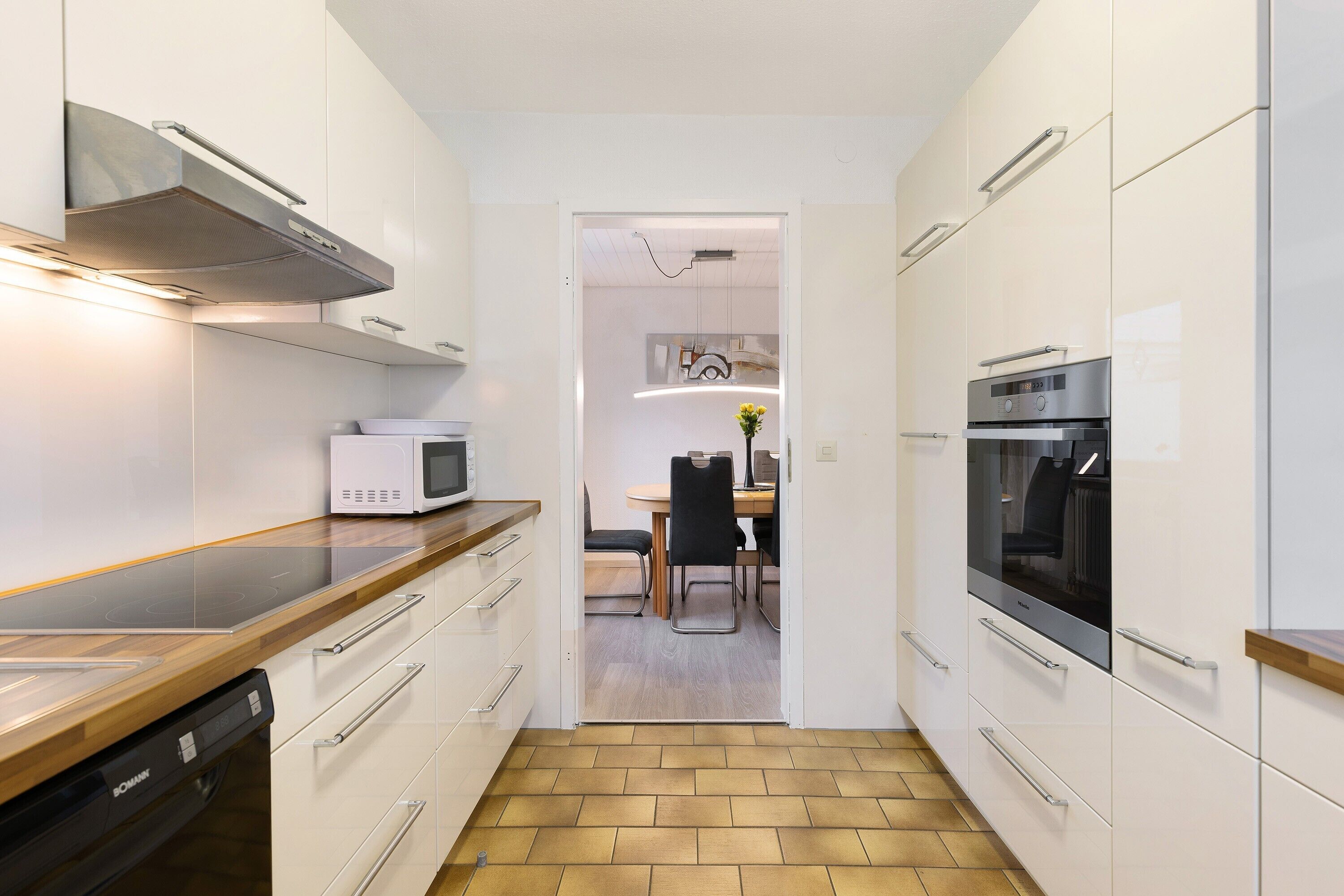 A modern kitchen with white cabinetry, a built-in microwave, and a dishwasher.