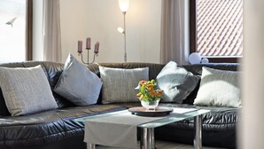 Una sala de estar moderna con un sofá de cuero, una mesa de centro de vidrio y un jarrón con flores.