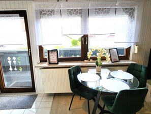 A dining area with a window seat, a radiator, and a small table with chairs. - Vacation apartment Dahlie, 60 sqm, 1 bedroom, max. 3 persons (Münsingen)
