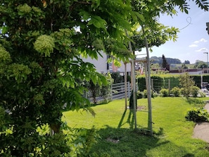 A well-maintained garden with a wooden play structure, a metal fence, and a grassy area. - Vacation apartment Dahlie, 60 sqm, 1 bedroom, max. 3 persons (Münsingen)