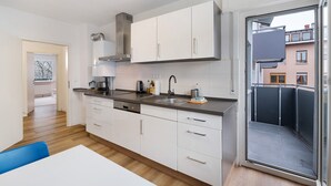 Een moderne keuken met witte kasten, een roestvrijstalen afzuigkap en een groot raam.