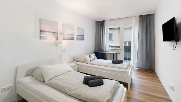 Een hotelkamer met twee bedden, een bureau, een televisie en een raam met gordijnen.