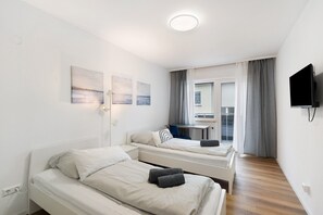 Ein Hotelzimmer mit zwei Betten, einem Schreibtisch, einem Fernseher und einem fenster mit Vorhängen.