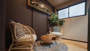 Une pièce chaleureuse avec deux fauteuils en osier, un petit pouf et une plante en pot.