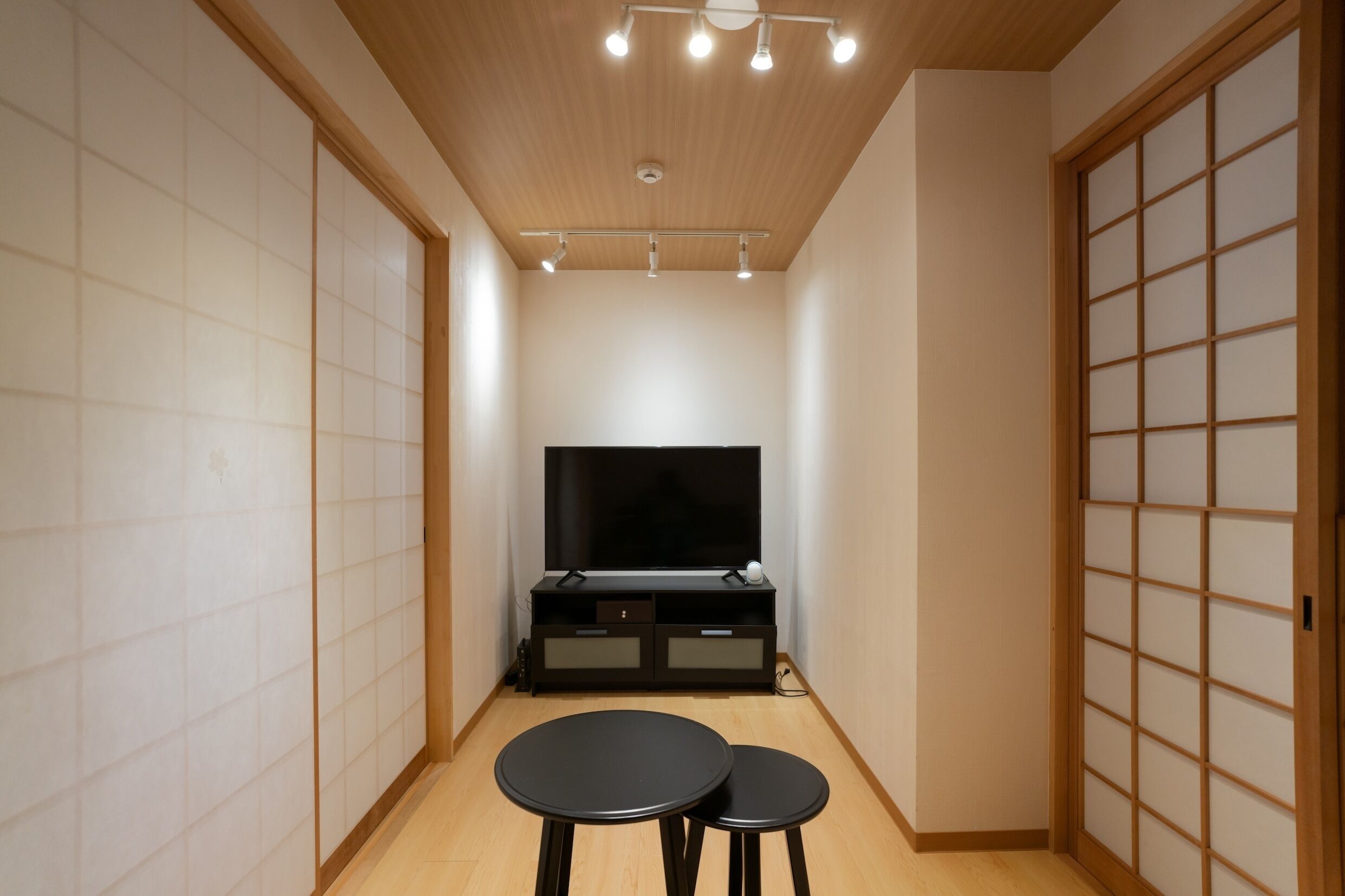A room with a TV, a small table, and sliding doors.