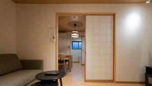 Un salon comprenant un canapé, une petite table et un coin repas avec des chaises et une table.