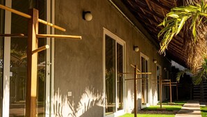 A modern building with large windows, a concrete pathway, and a thatched roof structure.