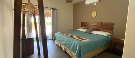 A bedroom with a bed, wooden headboard, bedside tables, and a hanging light fixture.