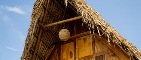 A thatched-roof building with a wooden balcony and a concrete base.