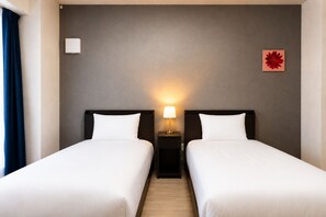A hotel room with two beds, a nightstand with a lamp, a wall-mounted air conditioner, and a single flower decoration. - Hotel Piacere Namba (Osaka)