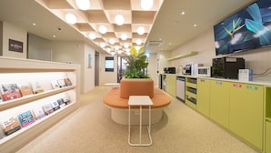 A modern interior with a central seating area, a bookshelf, and a kitchen area. - Workers Hotel Ansan by Anook (Ansan)