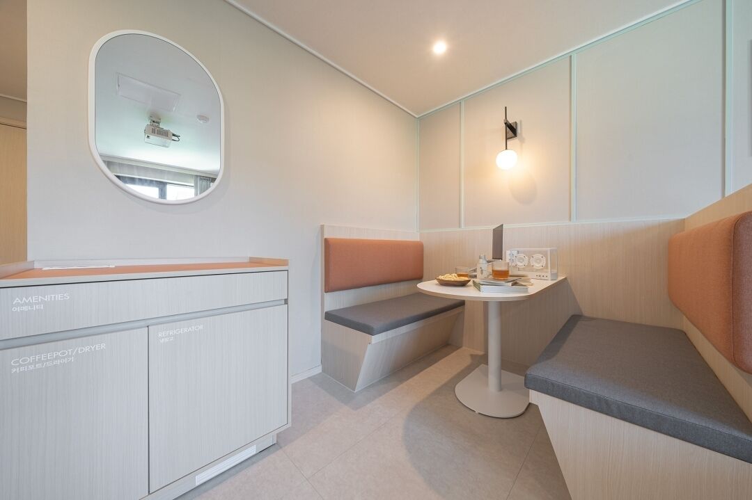A compact room with a kitchenette, a round table with a bench, and a small seating area.