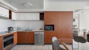Una cocina moderna con armarios blancos y marrones, electrodomésticos de acero inoxidable y suelo de baldosas.