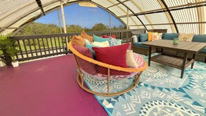 A cozy interior with a cushioned seating area, a table, and a view through a corrugated metal roof.