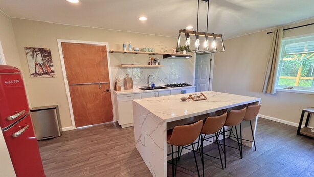 A modern kitchen with a marble island, bar stools, and a built-in oven.