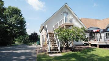 A two-story house with a front porch, a staircase leading to the second floor, and a small tree in the front yard.
