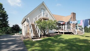 Ein zweigeschossiges Haus mit einer Veranda, einem kleinen Baum und einer Wäscheleine.