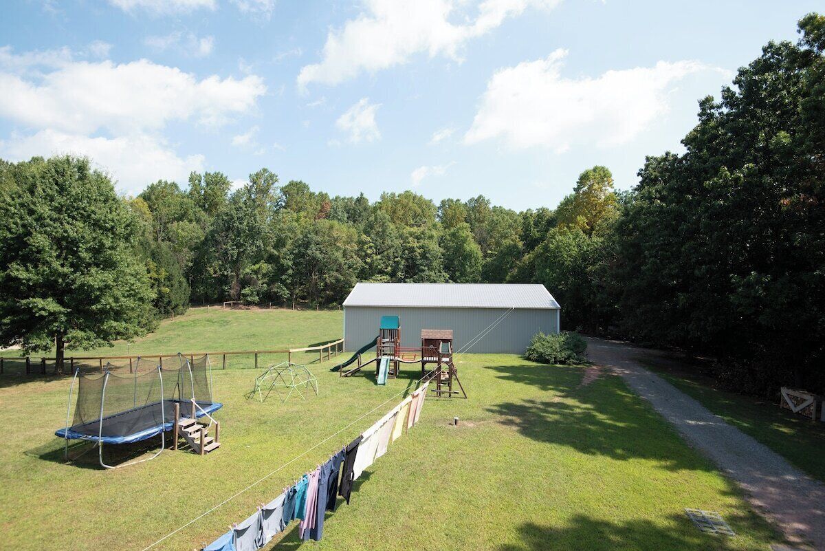A grassy yard with a trampoline, a playhouse, and a shed.