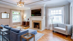 Un salon spacieux avec une cheminée, un grand canapé, un téléviseur fixé au-dessus de la cheminée et un lampadaire.