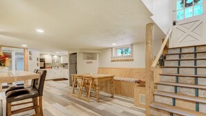 A spacious kitchen with wooden cabinets, a dining area with a bench, and a staircase with a decorative window.