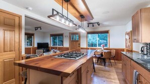 Una cocina moderna con armarios de madera, una isla central con estufa e iluminación colgante.