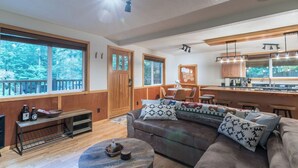 Una sala de estar moderna con un sofá grande, una mesa de centro y un comedor con una cocina al fondo.