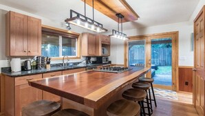 Una cocina moderna con armarios de madera, una isla central con taburetes y un ventanal con vistas a un patio trasero.