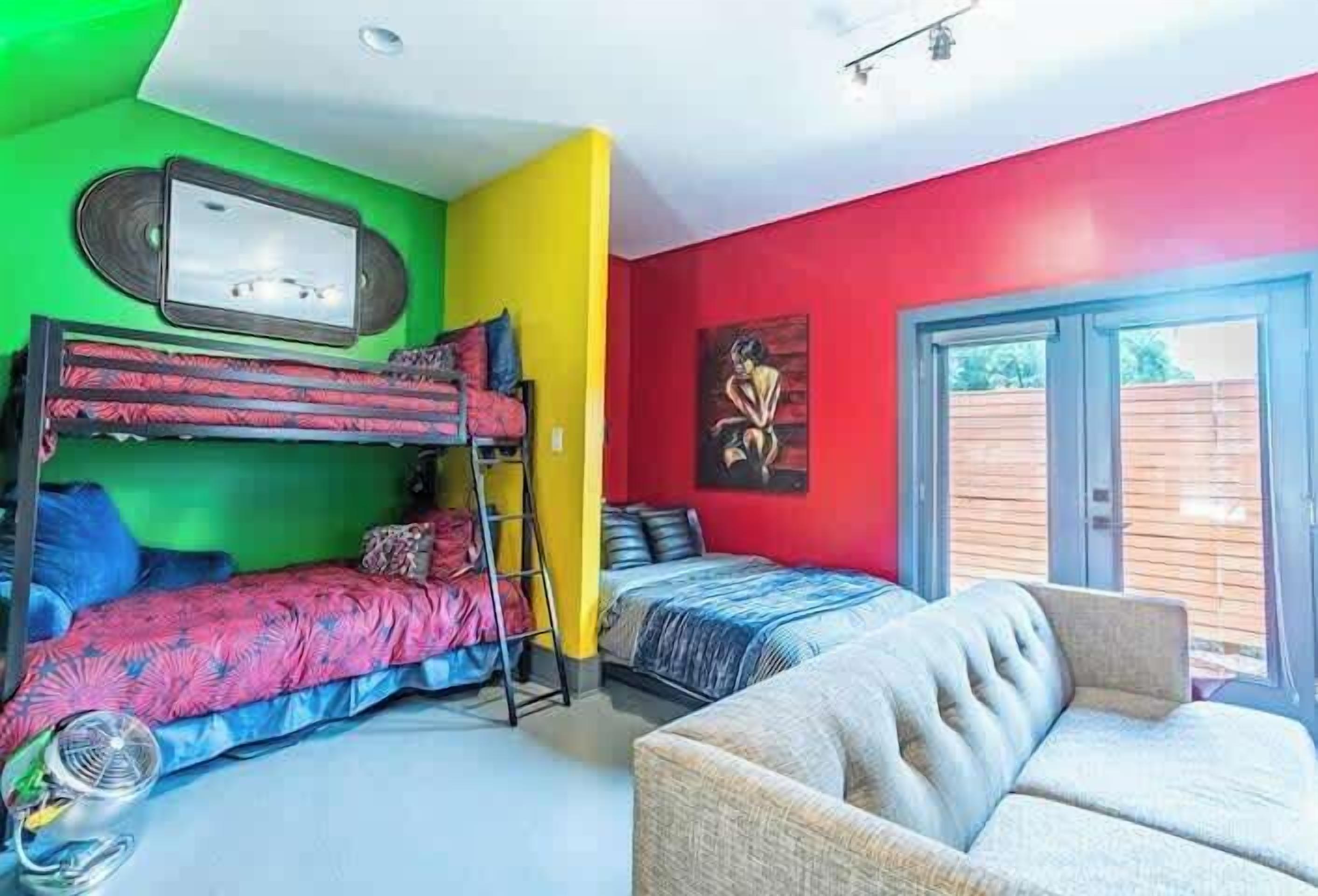 A room with bunk beds, a sofa, a painting, and a window.