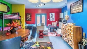 Uma sala de estar vibrante com sofá, mesa de centro e uma área de jantar com cadeiras e mesa.