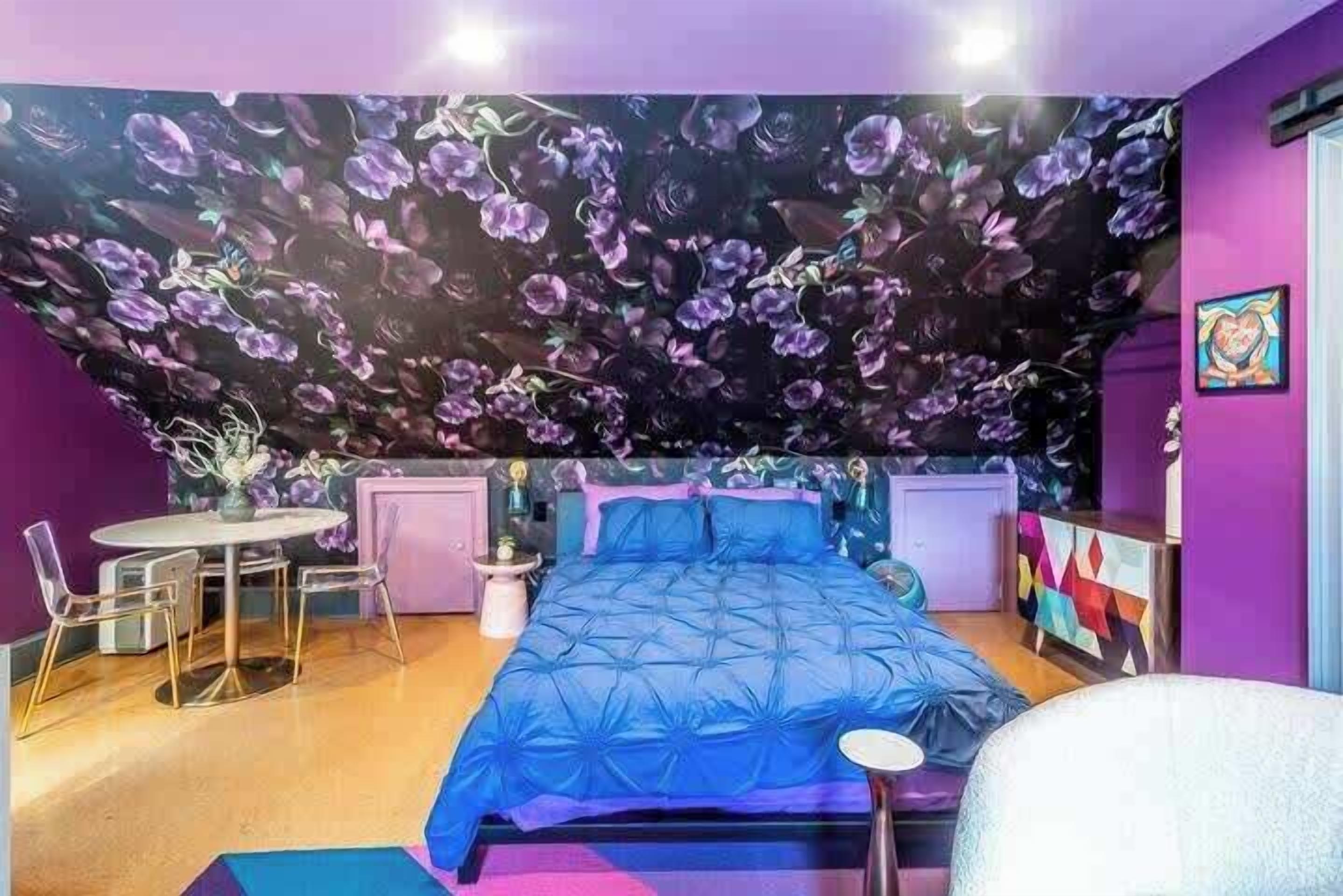 Un dormitorio con una cama grande, una mesa de comedor redonda y una mesita auxiliar.
