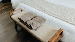 Una cama bien hecha con edredón blanco y una manta tejida color beige.